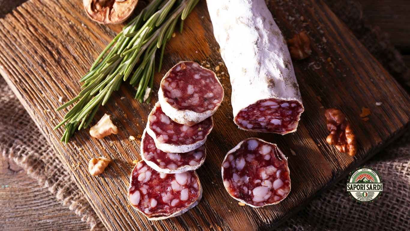 Aufgeschnittene Salami auf einem Holzbrett. Verziert mit Rosmarin. Unten rechts ist das Logo von Sapori Sardi zu sehen.