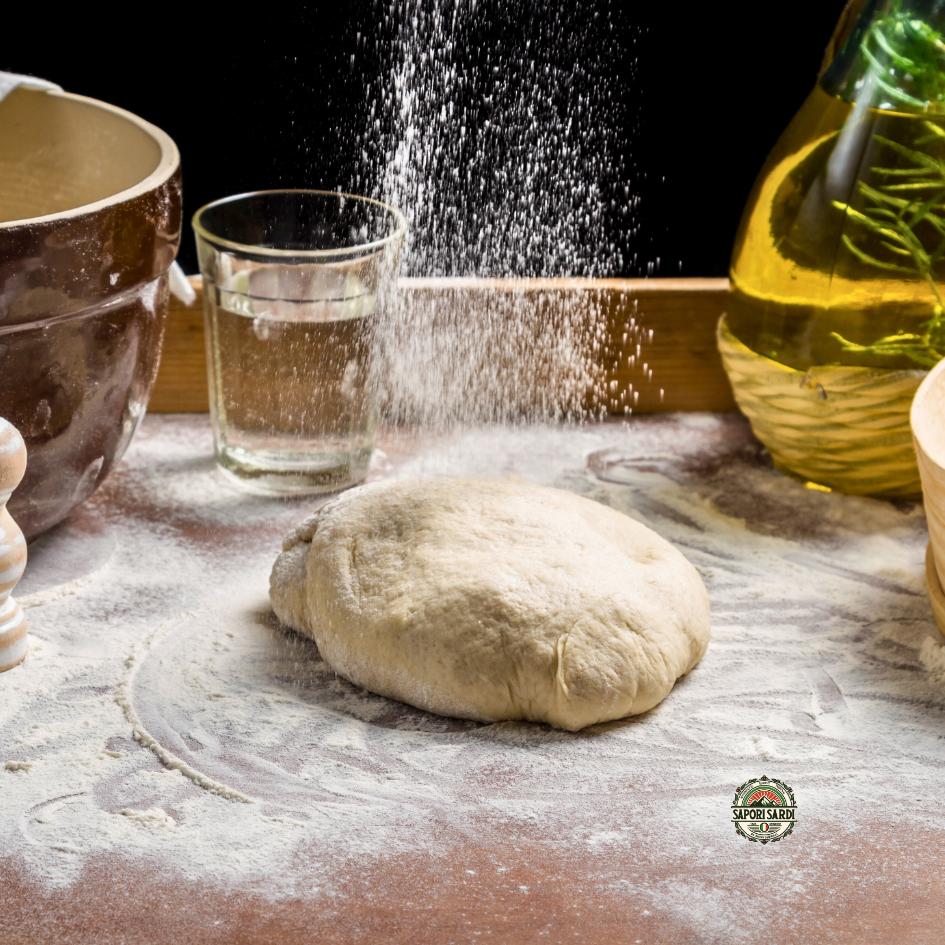 Frischer Pizzateig in kleinen Kugeln, bereit zum Ausrollen, mit einem hölzernen Nudelholz im Hintergrund auf einer bemehlten Oberfläche in einer Küche.