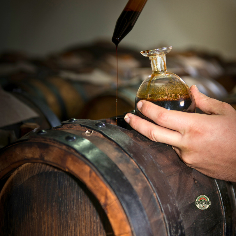 BIO Aceto Balsamico di Modena im Holzfass. Eine Probe wird entnommen.