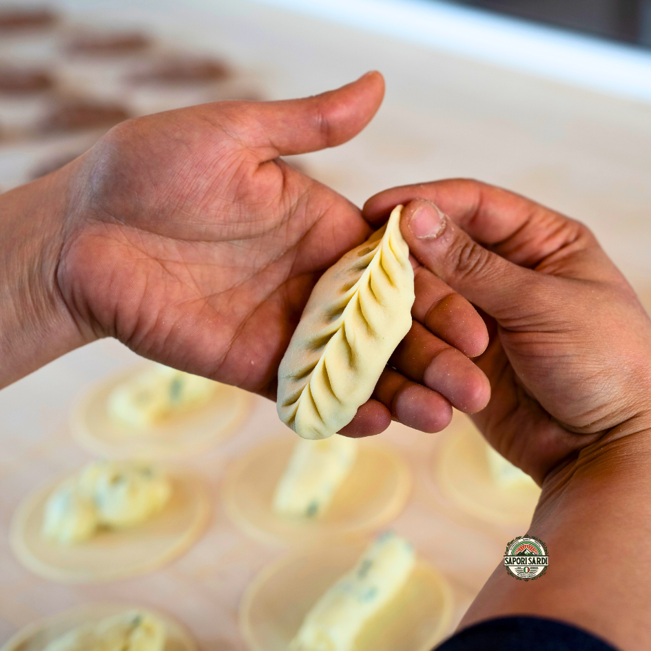 Culurgiones per Hand gefaltet. Eine Culurgiones wird in einer Handfläche präsentiert nachdem sie frisch gefüllt und gefaltet wurde.