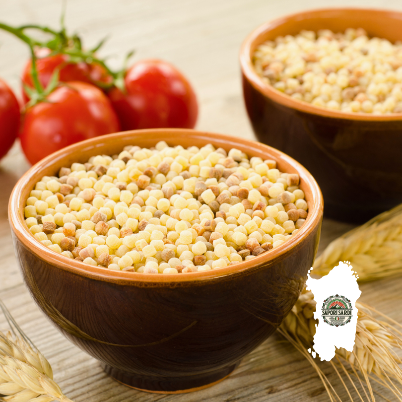 Fregola Sarda in braunen Schüsseln vorbereitet auf einem Holztisch. Auf dem Tisch liegt Weizen und Tomaten. Unten rechts im Bild ist das Logo von Sapori Sardi zu erkennen, welches auf einer weißen Karte von Sardinien liegt.