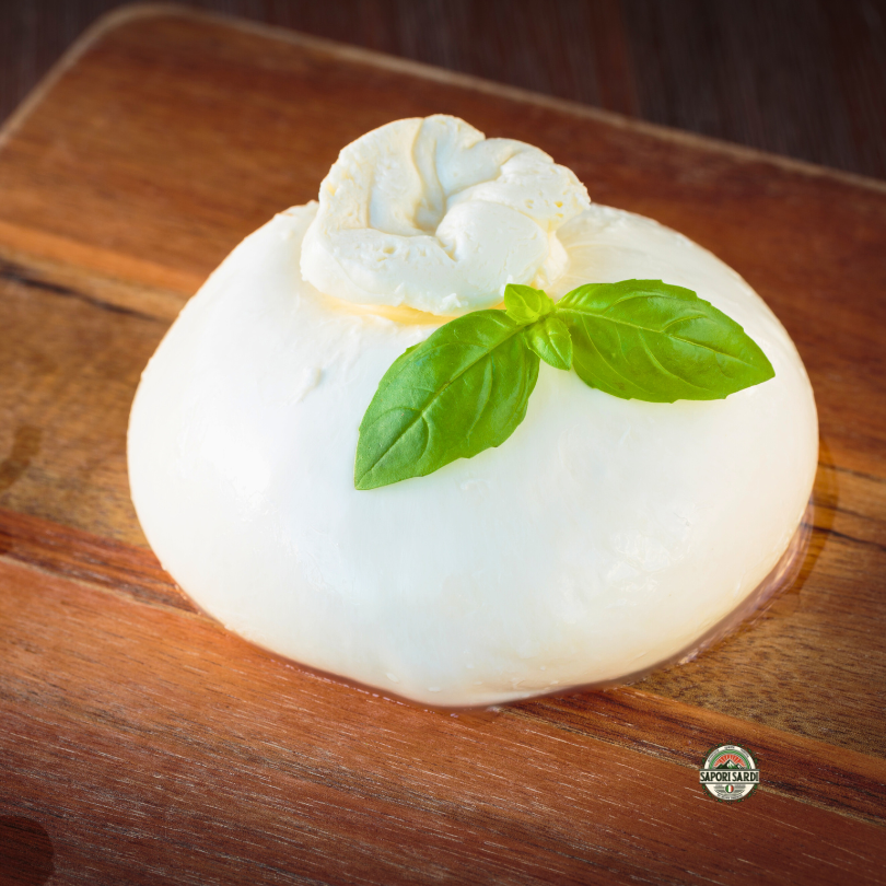 Frische Burrata auf einem Holzbrett mit etwas Basilikum verziert.