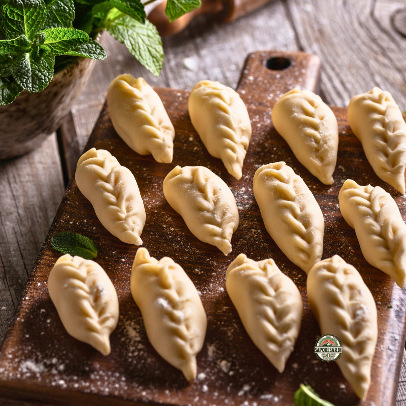 Handgemachte Culurgiones aus Sardinien. Traditionelle Pasta. Teigtaschen auf einem Holzbrett.