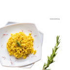 Risotto mit Safran aus Sardinien. Angerichtet auf einem Teller verziert mit Safran und einem Rosmarinzweig.