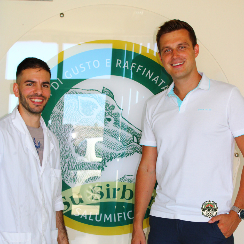 Su Sirboni und Sapori Sardi. Die Geschäftsführer beider Firmen vor dem Logo von Su Sirboni am Hauptsitz der Firma.