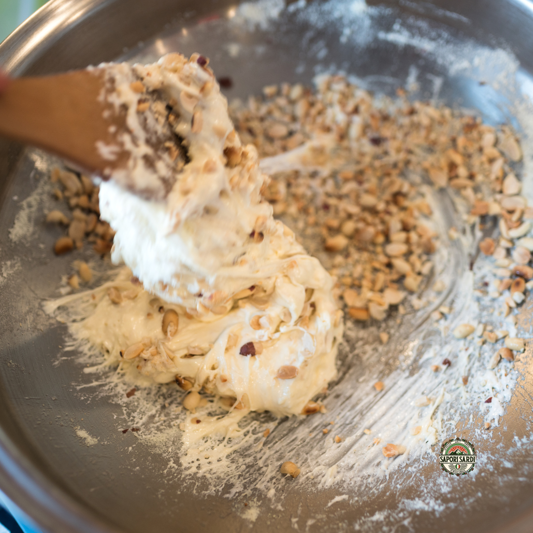 Torrone Masse wird in einer Schale angerührt. Es werden Nüsse untergerührt. Unten rechts ist das Logo von Sapori Sardi zu sehen.
